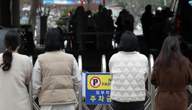 20일 강원 춘천시 한 초등학교에 마련된 임시 선별진료소에서 어린이들이 신종 코로나바이러스 감염증(코로나19) 검사를 받는 모습을 학무보들이 교문 너머로 지켜보고 있다. 연합뉴스