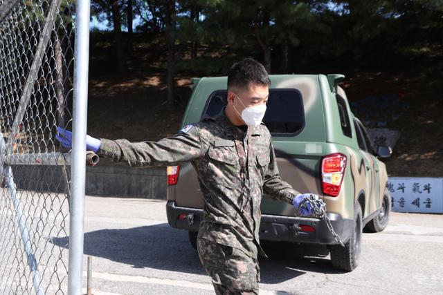 지난달 5일 경기도 포천시의 한 육군 부대에서 군 관계자가 마스크와 장갑을 착용한 채 문을 닫고 있는 모습. 사진은 기사와 직접 관련 없음. 연합뉴스