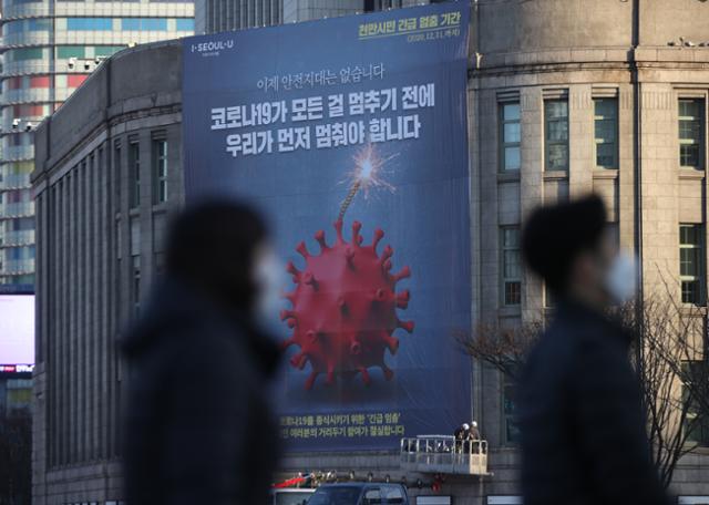 25일 오전 서울도서관 외벽에 천만 시민 긴급 멈춤 기간을 알리는 대형 현수막이 설치되고 있다. 연합뉴스