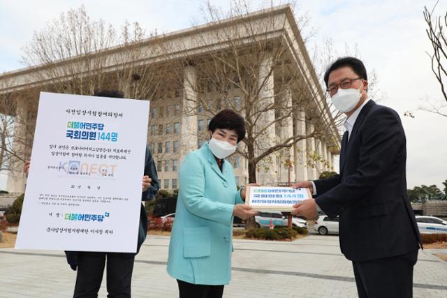 전혜숙(가운데) 더불어민주당 국난극복 K-뉴딜위원회 공동위원장이 27일 국회에서 코로나19 임상 사전 참여의향서 발표 기자회견을 마친 뒤 배병준 국가임상시험지원재단 이사장에게 사전임상시험 참여의향서를 전달하고 있다. 오대근 기자