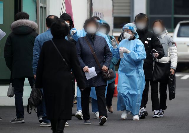 27일 오전 서울 중구 국립중앙의료원에 마련된 선별진료소에서 의료진들이 내원객에게 코로나19 검체 채취 전 안내를 하고 있다. 뉴스1