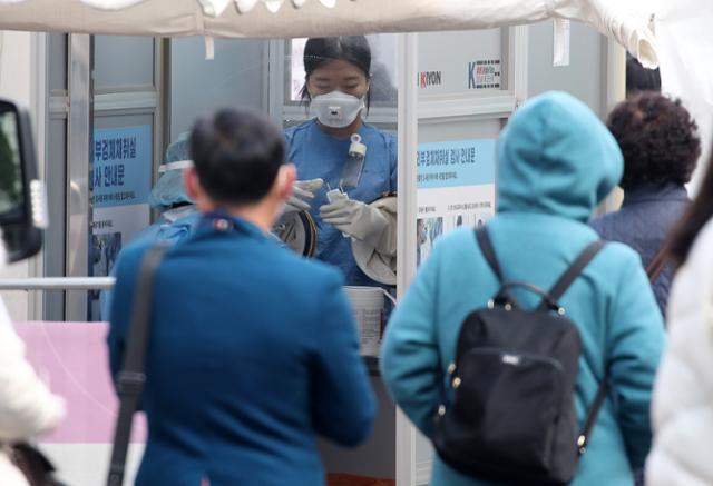 27일 오전 서울 중구 국립중앙의료원에 마련된 선별진료소에서 의료진이 내원객에게 코로나19 검체 채취를 하고 있다. 뉴스1