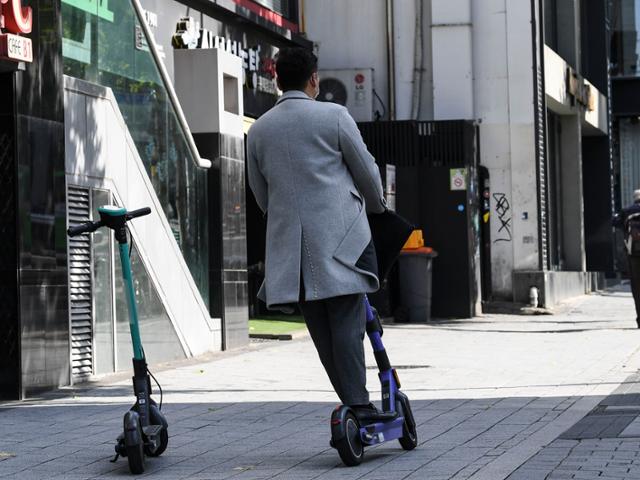 3일 서울 마포구 홍익대 인근 보행도로 한복판에 주차된 공유 전동 킥보드 옆으로 다른 전동 킥보드 이용객이 지나고 있다. 이한호 기자