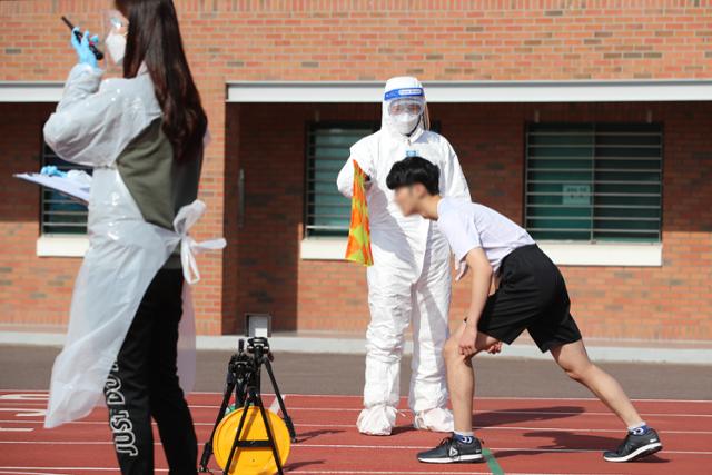 지난달 5일 대구 달서구 계명대 성서캠퍼스에서 열린 2021학년도 신입생 수시모집 예체능전형 체육대학 태권도학과 실기고사에서 100m달리기에 응시하는 수험생이 레벨D 방호복과 보호장구를 착용한 채점위원 옆에서 준비를 하고 있다.대구=뉴스1