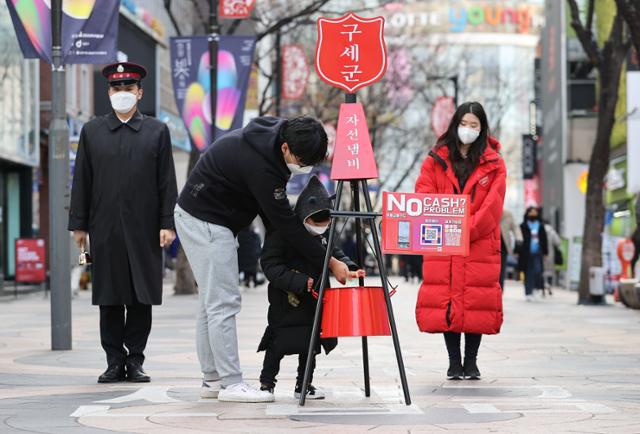 1일 오후 서울 중구 명동 거리에서 한 어린이가 아빠와 함께 구세군 자선냄비에 성금을 넣고 있다. 연합뉴스