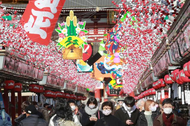 지난 16일 마스크를 쓴 일본 시민들이 새해를 맞아 화려하게 장식된 아사쿠사 센소지로 향하는 길을 지나고 있다. 뉴시스