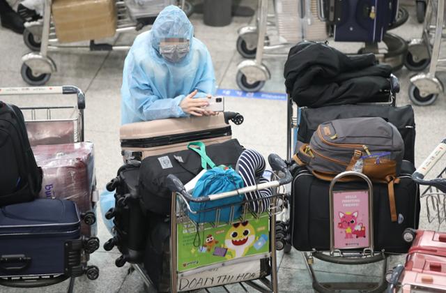 영국발 변이 코로나19 바이러스가 국내에서 처음 확인된 28일 오전 인천국제공항 1터미널 입국장에서 방호복을 입은 해외 입국객이 대기하고 있다. 영종도=연합뉴스