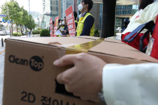 지난해 9월 23일 오전 서울 중구 서울고용노동청 앞에서 민주노총 서비스연맹 마트산업노동 조합원들이 기자 회견을 열고 근골격계 질환 해결을 위해 상자에 손잡이 설치를 요구한 지 1년이 지났다며 고용노동부에 빠른 설치를 촉구하고 있다. 한 노조원이 포장 상자에 구멍을 뚫어 들고 있다. 뉴스1