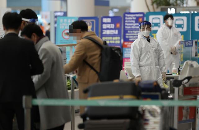 30일 오후 인천국제공항 제2여객터미널 입국장에서 일본 오사카발 항공편 해외입국자들이 방역 관계자들의 안내를 받고 있다. 연합뉴스