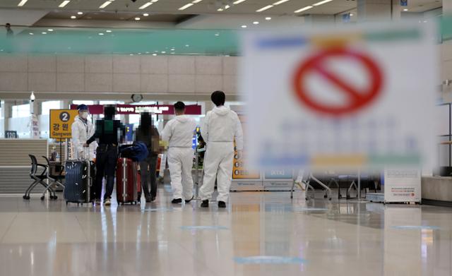 코로나19 확산세가 계속되는 지난 27일 인천국제공항 제1터미널 입국장에서 관계자들이 입국자들에게 동선 안내를 하고 있는 모습. 연합뉴스