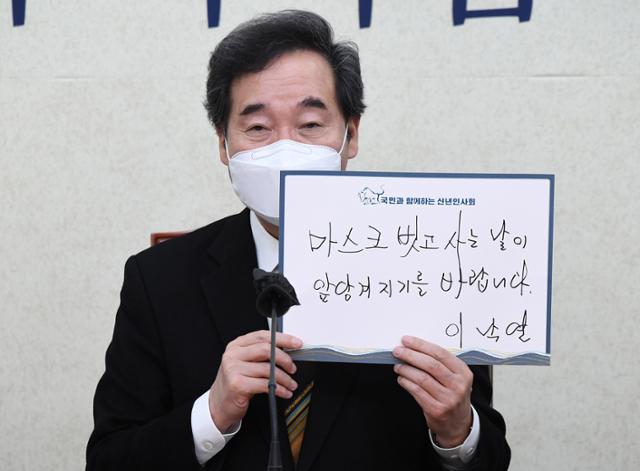 이낙연 더불어민주당 대표가 7일 '2021년 신년 인사회'에 화상으로 참가해 '마스크 벗고 사는 날이 앞당겨지기를 바랍니다'라고 쓴 손팻말을 들고 기념촬영을 하고 있다. 오대근 기자