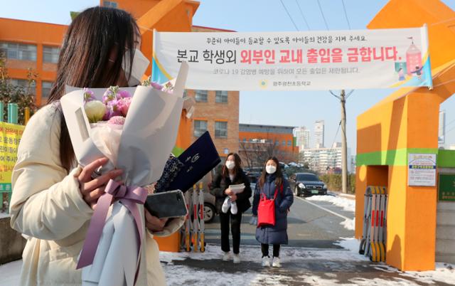 12일 오전 광주 서구 광천초등학교 후문에서 졸업식을 마치고 나온 학생이 학교를 바라보고 있다. 이날 졸업식은 신종 코로나바이러스 감염증(코로나19) 감염을 우려해 졸업생을 제외한 학부모 등은 참석이 제한됐다. 연합뉴스