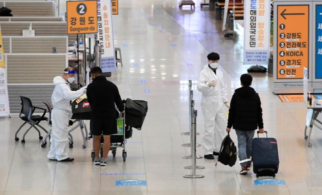 14일 오후 인천국제공항 제1터미널 입국장에서 방역 관계자들이 입국하는 승객들을 안내하고 있다. 인천공항=뉴시스