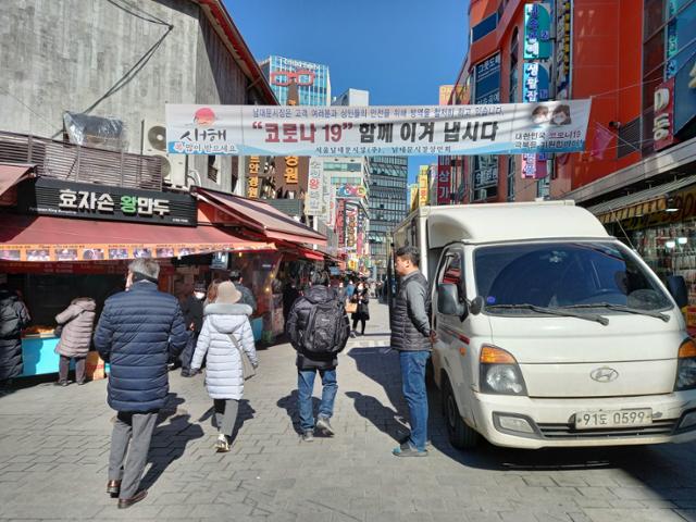 8일 오후 서울 중구 남대문시장에 걸려 있는 '코로나19 극복' 현수막 아래를 손님들이 지나가고 있다. 최다원 기자