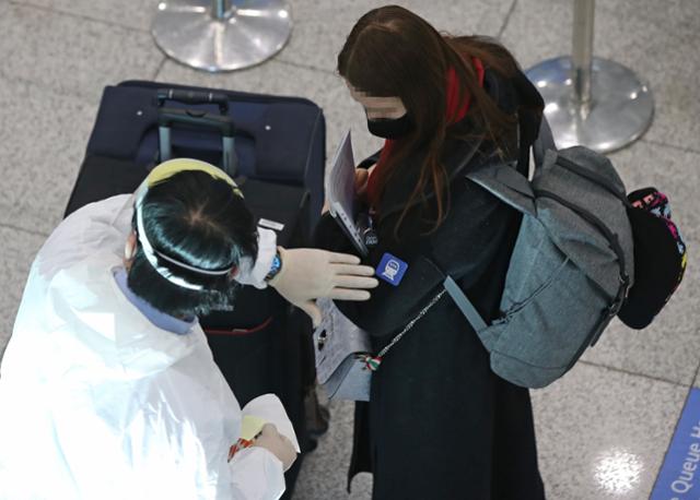 설 연휴를 이틀 앞둔 9일 오전 인천국제공항 제1여객터미널 입국장에서 관계자가 해외 입국자 어깨에 식별 스티커를 붙이고 있다. 연합뉴스