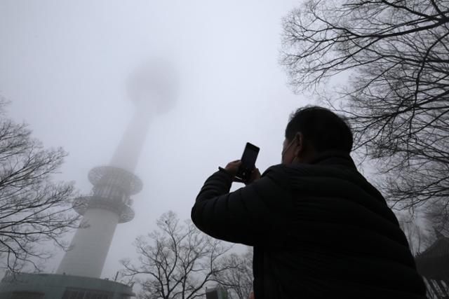 수도권을 비롯한 전국 곳곳에서 고농도 미세먼지가 한때 매우 나쁨 수준까지 치솟은 7일, 한 시민이 흐릿한 남산 서울타워를 휴대폰으로 촬영하고 있다. 뉴스1