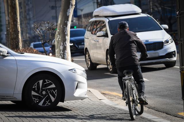 지난 9일 서울 관악구의 한 커피전문점 DT 매장에서 나오는 차량 앞으로 자전거 이용자가 아슬아슬하게 지나가고 있다. 도심에 위치한 드라이브 스루 매장의 차량 진출입로는 대부분 보행자 인도를 가로지르는 형태로 설계돼 있다.