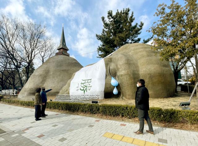 대구 시민들이 달서구 상화로 거대 원시인 조형물에 설치된 코로나19 희생자 추모 퍼포먼스를 보며 거리를 지나고 있다. 달서구 제공