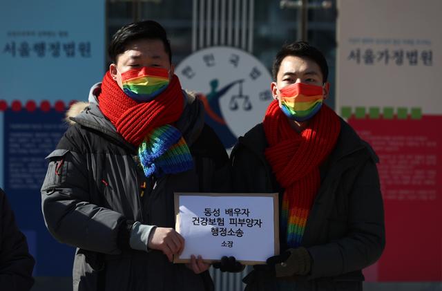 18일 오전 서초구 서울행정법원 앞에서 열린 '동성 배우자 건강보험 피부양자 소송 기자회견'에서 소송 당사자 소성욱-김용민 부부가 소장을 들어보이고 있다. 연합뉴스