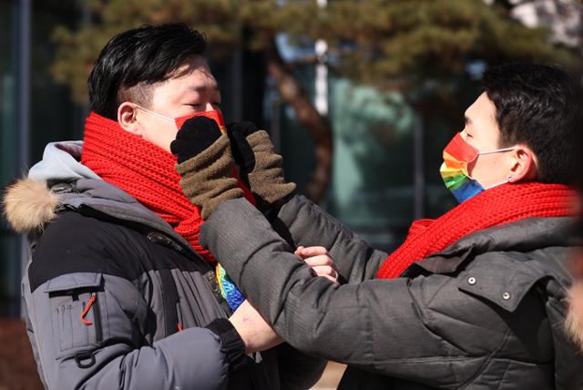 18일 오전 서초구 서울행정법원 앞에서 소송 당사자 소성욱(왼쪽)·김용민 부부가 '동성 배우자 건강보험 피부양자 소송 기자회견' 시작에 앞서 서로의 마스크와 목도리를 고쳐주고 있다. 연합뉴스