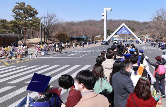 26일 서울 관악구 서울대학교에서 이날 학위를 받은 졸업생과 가족들이 학교 정문을 배경으로 기념사진을 찍기 위해 줄지어 차례를 기다리고 있다. 신종 코로나바이러스 감염증(코로나19) 확산으로 이날 서울대 학위수여식은 온라인 실시간 재생 방식으로 열렸다. 연합뉴스