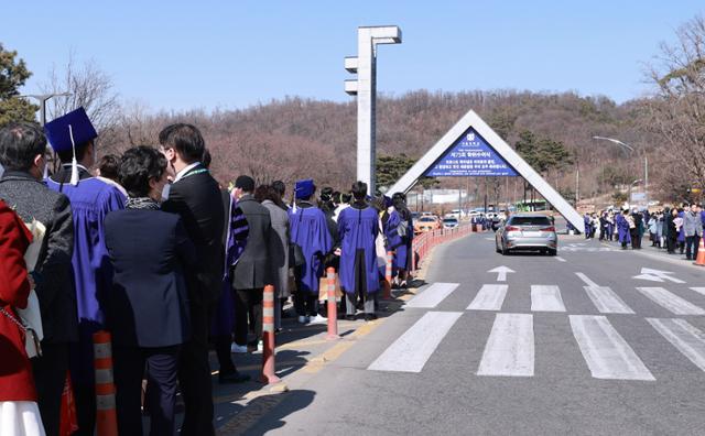 26일 서울 관악구 서울대학교에서 이날 학위를 받은 졸업생과 가족들이 학교 정문을 배경으로 기념사진을 찍기 위해 줄지어 차례를 기다리고 있다. 신종 코로나바이러스 감염증(코로나19) 확산으로 이날 서울대 학위수여식은 온라인 실시간 재생 방식으로 열렸다. 연합뉴스