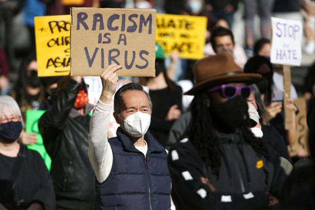 13일 미국 워싱턴주 시애틀에서 열린 인종차별 반대 집회에서 한 남성이 '인종차별은 바이러스'라고 적힌 팻말을 들고 있다. 시애틀=AFP 연합뉴스