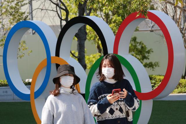 17일 일본 도쿄에서 마스크를 쓴 행인들이 오륜 조형물 앞을 지나가고 있다. 도쿄=AP 연합뉴스