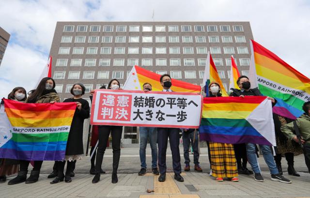 일본 삿포로(札幌)지방재판소가 17일 동성 간의 결혼을 인정하지 않는 것은 헌법에 위배된다고 판결하자 원고 측 변호인과 동성결혼 지지자들이 법원 앞에서 '위헌 판결'이라고 적힌 플래카드를 들고 기뻐하고 있다. 일본 법원이 동성혼 불인정에 대해 위헌 판단을 내린 것은 이번이 처음이다. 삿포로=지지통신 AFP 연합뉴스