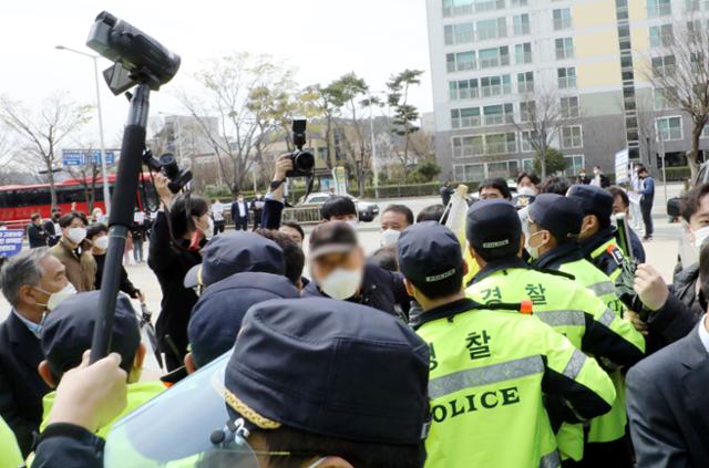 24일 오전 광주 서구 치평동 김대중컨벤션센터 앞에서 한 오월단체 회원이 김종인 국민의힘 비상대책위원장 차량을 막아서 경찰의 제지를 받고 있다. 뉴스1