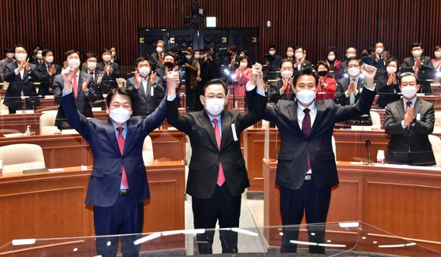 안철수(왼쪽부터) 국민의당 대표와 주호영 국민의힘 원내대표, 오세훈 후보가 24일 국회에서 열린 국민의힘 의원총회에 참석해 단일화 성공을 기념하는 의미로 두 손을 들고 포즈를 취하고 있다. 오대근 기자