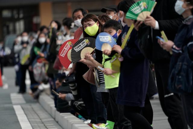 25일 일본 동북부 후쿠시마현 나라하의 2020 도쿄올림픽 성화봉송 제1 구간 봉송로에서 코로나19 확산 방지를 위해 마스크를 쓴 현지 주민들이 성화봉송 주자들을 기다리고 있다. 성화 봉송은 도쿄올림픽 개막식이 열리는 7월23일까지 121일 동안 일본 전역을 돌면서 진행된다. 나라하 AP=뉴시스