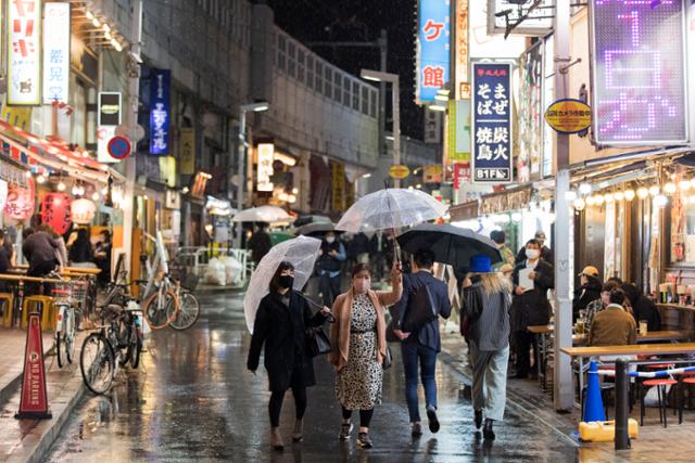 일본 수도권에 발령됐던 신종 코로나바이러스 감염증(코로나19) 긴급사태가 전면 해제된 지난 22일 밤 마스크를 착용한 시민들이 음식점과 술집이 밀집한 도쿄 유흥가를 걸어가고 있다. 도쿄=AP 연합뉴스