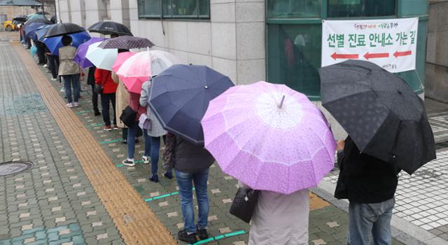 12일 서울 중랑구 보건소에 마련된 신종 코로나바이러스 감염증(코로나19) 선별 진료소에서 시민들이 우산을 쓰고 차례를 기다리고 있다. 뉴시스