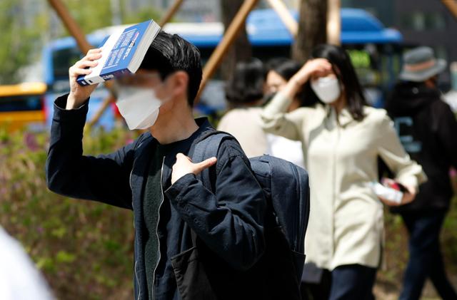 서울 낮 최고 기온이 28도로 무더운 날씨를 보인 21일 서울 중구 청계광장 인근에서 시민들이 책과 손으로 햇빛을 가리고 있다. 뉴시스