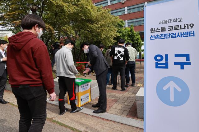 26일 오전 서울 관악구 서울대학교 자연과학대 앞에서 이 대학교가 도입한 신종 코로나바이러스 감염증(코로나19) 신속 분자진단 검사를 받은 대학원생 등 학생들이 검사를 마친 뒤 검체를 보관함에 넣고 있다. 연합뉴스