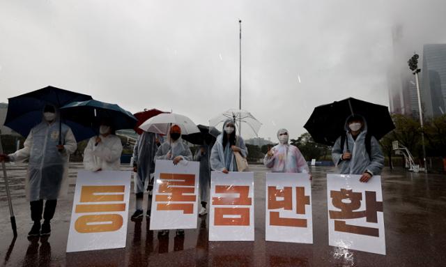 3일 오후 서울 여의도공원에서 2021등록금반환운동본부 주최로 열린 등록금 반환 요구 10km 릴레이 행진에서 참가자들이 행진 출발 전, 요구사항이 담긴 팻말을 들고 있다. 연합뉴스