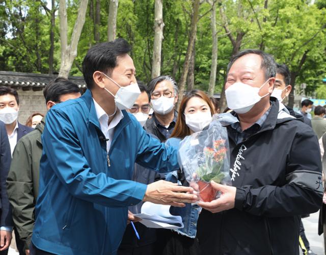 오세훈(왼쪽) 서울시장이 6일 오전 서울 종로구 세종대로 사람숲길에서 구매한 꽃을 김인호 서울시의회 의장에게 선물하고 있다. 서울시는 세종대로 사거리에서 서울역까지 1.55㎞ 구간의 차로를 줄이고 보행로 폭을 최대 12m까지 넓혀 세종대로 사람숲길 조성을 완료했다. 뉴스1