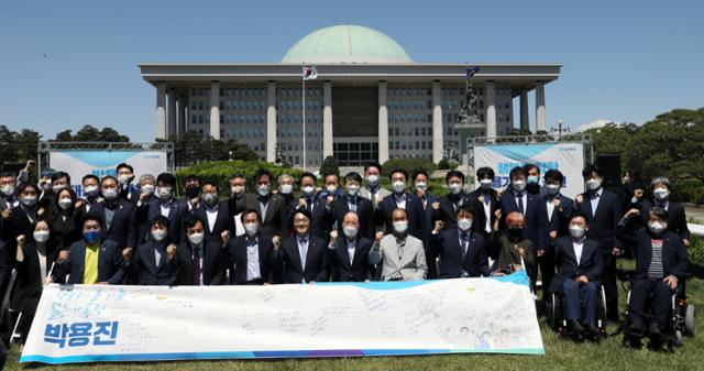 박용진(앞줄 왼쪽 여섯번째) 더불어민주당 의원이 9일 국회 잔디광장에서 제20대 대통령 선거 출마를 공식적으로 선언한 뒤 참석자들과 응원 메시지가 적힌 현수막을 들고 국회를 배경으로 기념촬영하고 있다. 연합뉴스