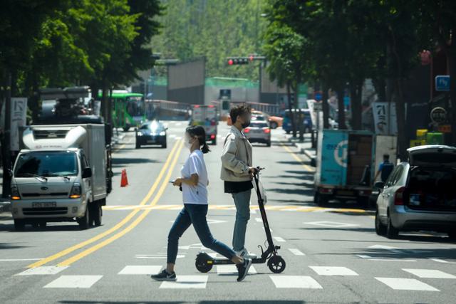 13일 오후 서울 마포구에서 한 전동킥보드 운전자가 안전모를 착용하지 않은 채 횡단보도를 건너고 있다. 7월부터는 범칙금 5만 원 부과 대상이다. 이한호 기자