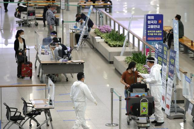 지난달 21일 인천국제공항 1여객터미널 입국장에서 입국자들이 방역 관계자의 안내를 받고 있다.뉴스1