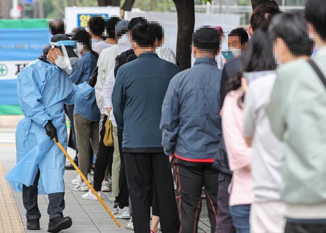 29일 오전 서울시 송파구 보건소 선별진료소에서 관계자가 코로나19 검사를 받기 위해 줄지어 서 있는 시민들에게 거리 두기를 안내하고 있다. 연합뉴스