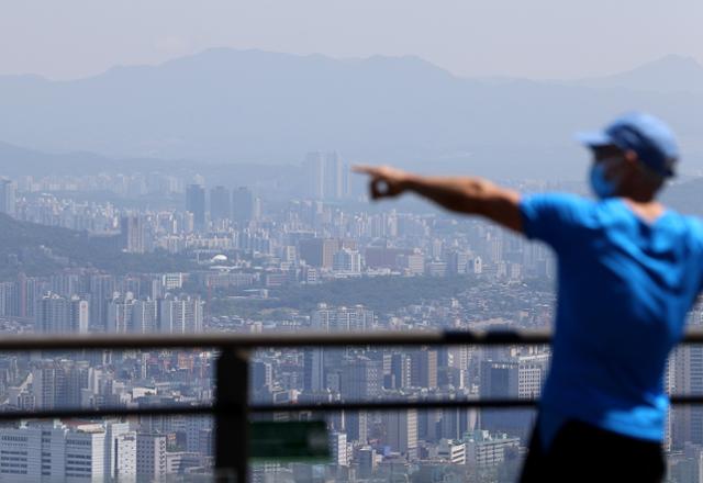 서울 남산을 찾은 시민이 아파트로 가득 찬 도심을 가리키고 있다. 연합뉴스