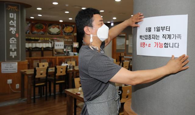 지난달 31일 대전 서구에 위치한 식당에서 식당 주인이 백신접종자는 직계가족 8인 이상 가능하다는 안내문을 붙이고 있다. 뉴스1