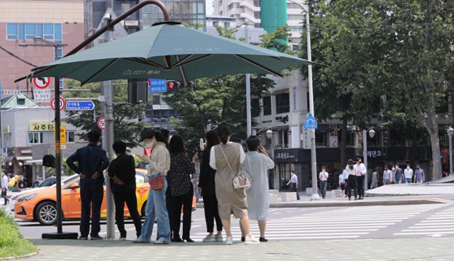 초여름 날씨를 보인 2일 서울 종로구 안국역 인근 그늘막 아래에서 시민들이 횡단보도 보행신호를 기다리고 있다. 뉴스1