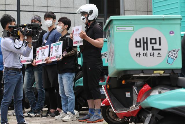 라이더유니온 관계자들이 16일 오후 서울 강남구 논현로 배민라이더스 남부센터 앞에서 피켓을 들고 라이더 백신 휴가 보장과 불공정한 AI 규제를 촉구하고 있다. 뉴스1