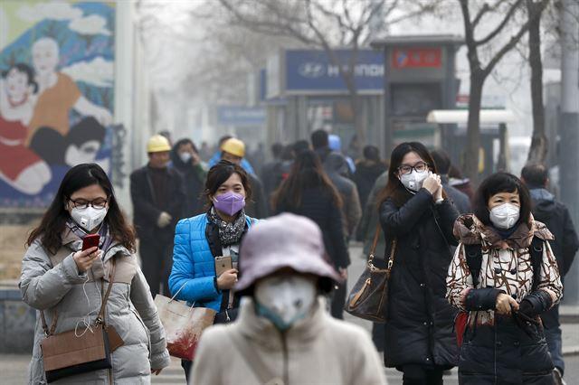 마스크를 쓴 중국 여성들이 베이징 시내를 걷고 있다. 2016년 12월 사진. 베이징=AP 연합뉴스