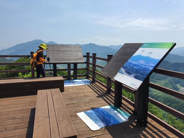 지난 28일 충북 괴산 성불산 3봉 전망대를 찾은 한 등산객이 아크릴로 제작된 경관 표지판이 산산 조각 난 채 바닥에 떨어진 모습을 둘러보고 있다. 이 관광객은 "등산 애호가들이 많이 찾는 명소의 기물을 이렇게 함부로 훼손해도 되는 거냐"고 반문했다. 괴산= 한덕동 기자