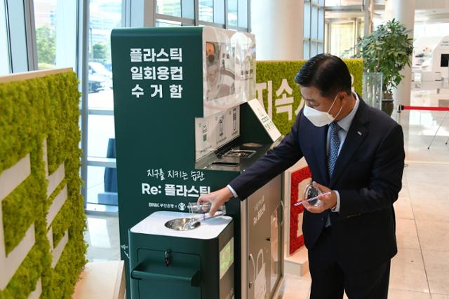 BNK부산은행 안감찬 은행장이 지난달 28일 본점 1층에서 ‘리플 캠페인(Re : Plastic)’의 일환으로 설치된 플라스틱 컵 수거함을 직접 사용하고 있다.