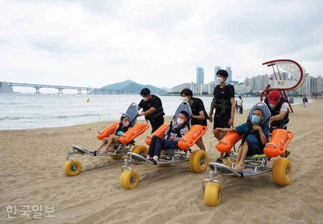 영도장애인자립생활센터의 장애인 3명이 수상휠체어를 타고 광안리해수욕장 바다로 이동하고 있다.